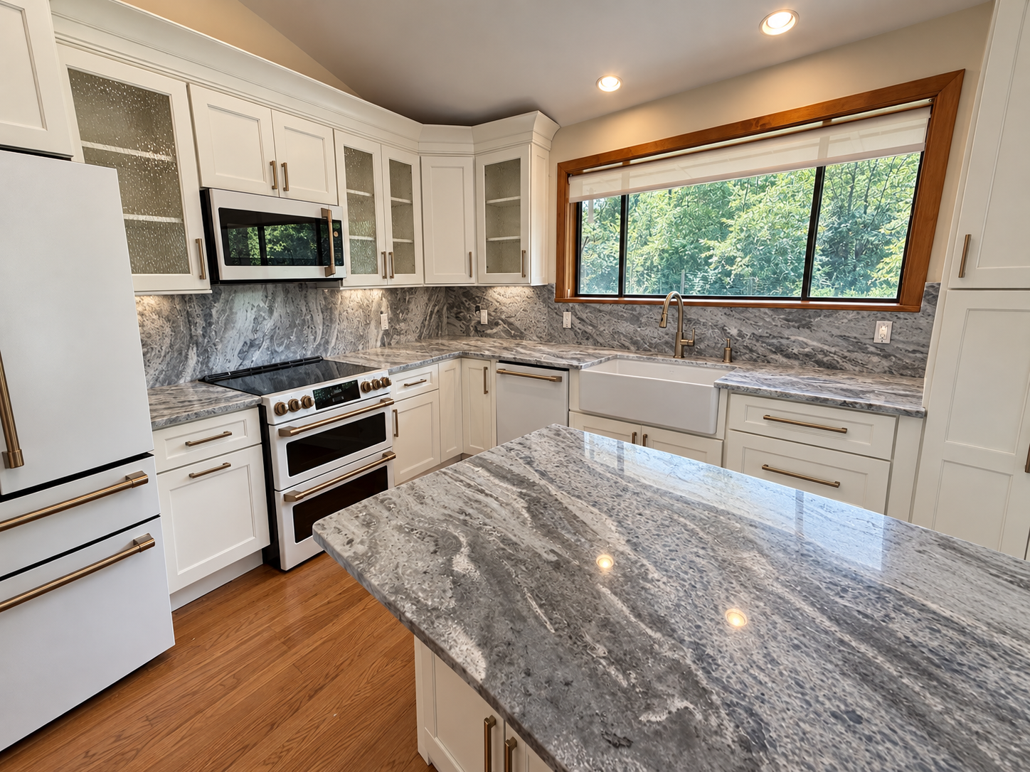 Renovated white kitchen with stone countertops, farmhouse sink, and brass fixtures